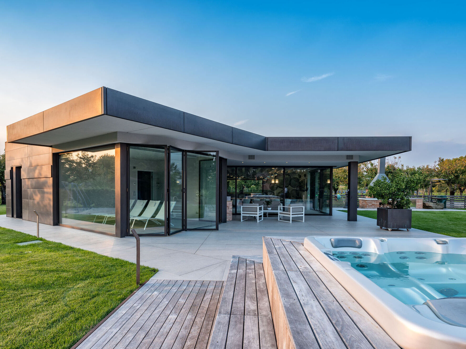 External view of the pool house with with motorized lift and slide doors and wide burnished brass fenestration